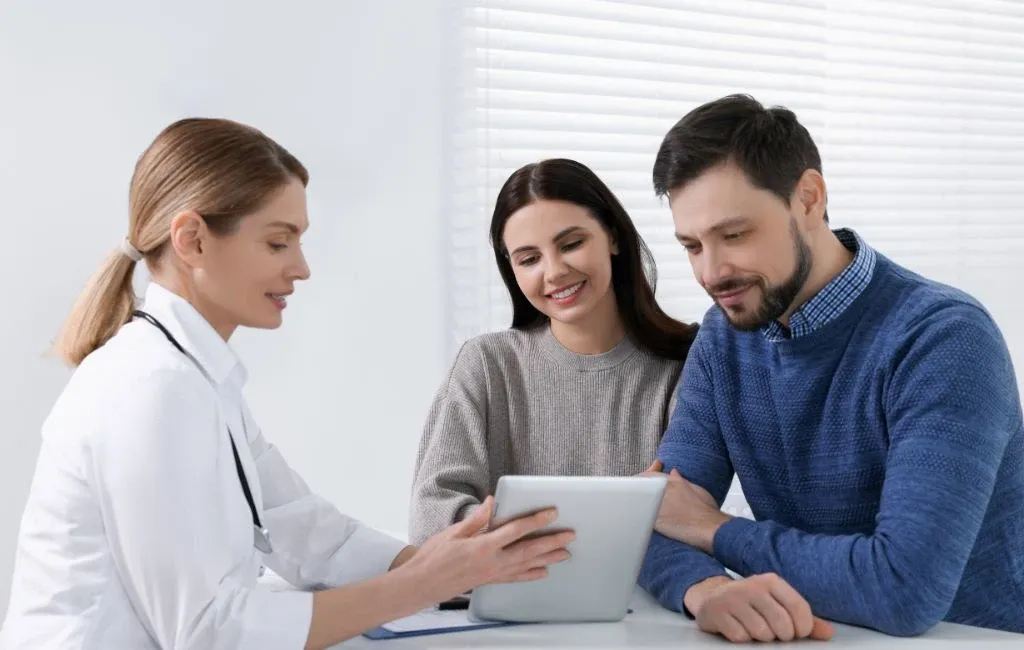 Egy orvos egy fiatal párral beszél a HPV és a szájüregi daganatok közötti összefüggésekről és a kezelési lehetőségekről.
